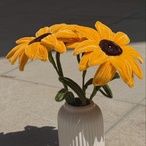 White vase with yellow sunflowers on a concrete surface